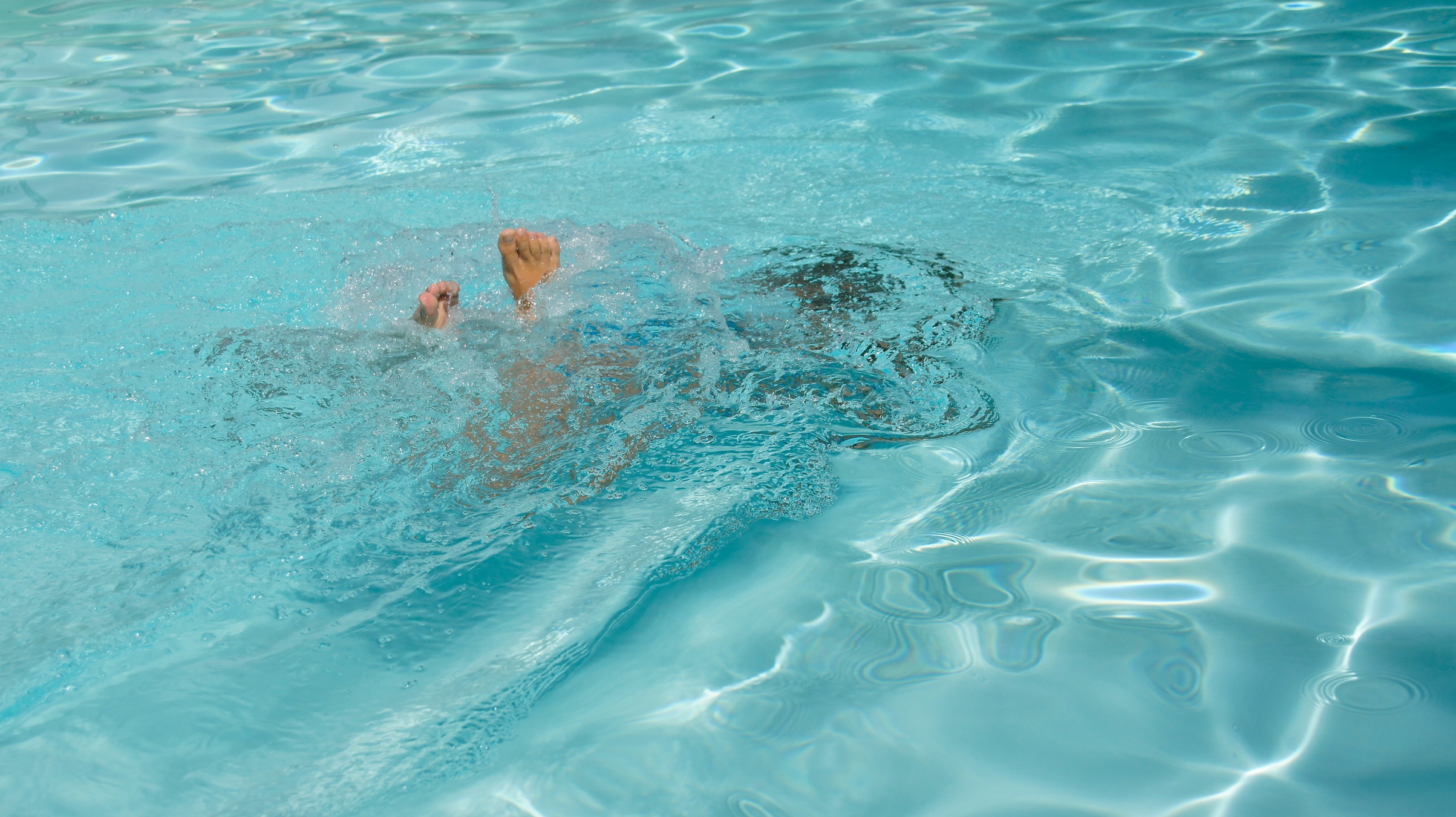 A man swimming in a pool with no shirt on
